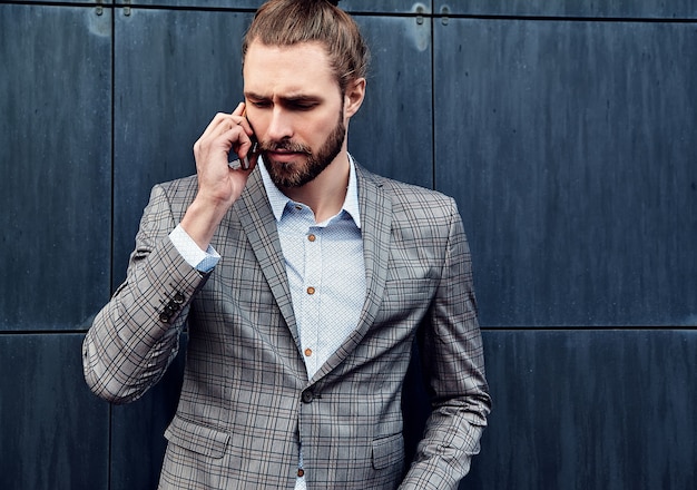 Gut aussehender Mann in der grauen karierten Klage, die mit Smartphone spricht