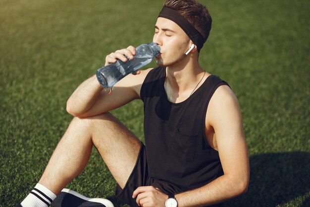 Gut aussehender Mann in einem Sport clother Trinkwasser in einem Park