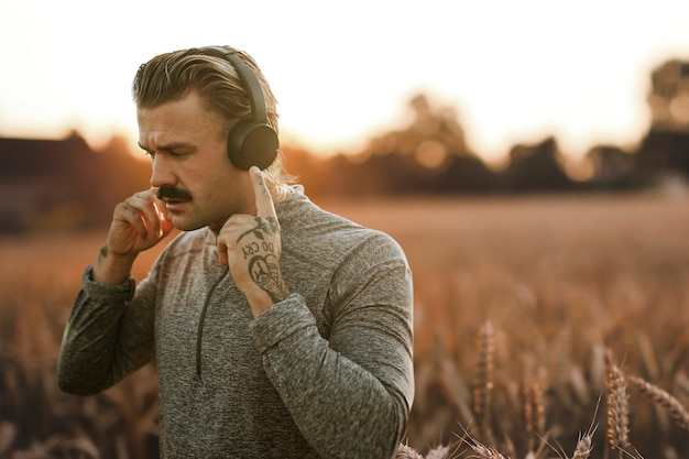 Gut aussehender Mann mit kabellosen Kopfhörern mit Naturansicht-Remixed-Medien