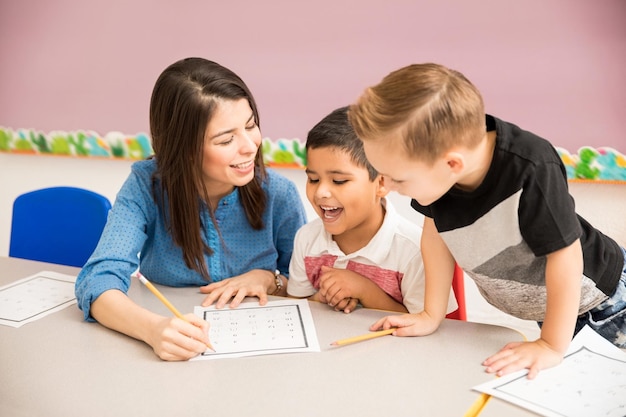 Gut aussehender Vorschullehrer und Schüler, die eine gute Zeit beim Lernen im Klassenzimmer haben