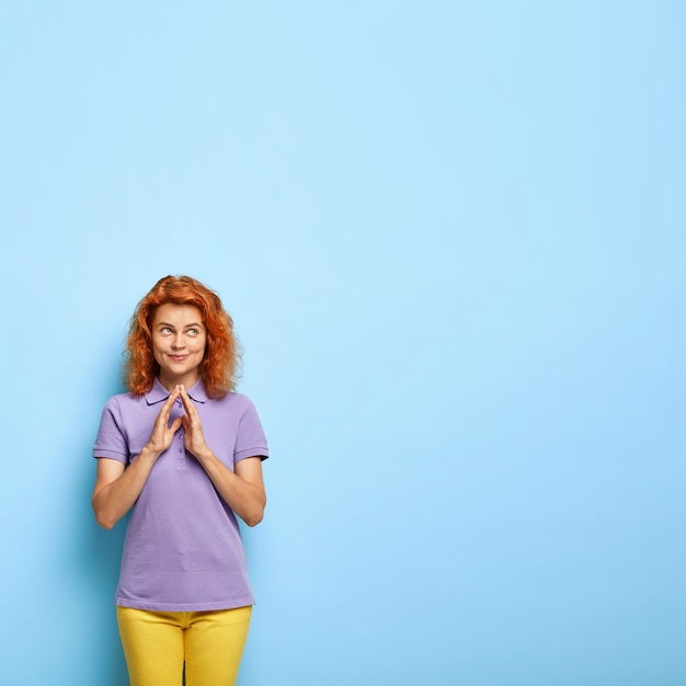 Kostenloses Foto gut aussehendes zufriedenes tausendjähriges mädchen hat schicke haare, hält die finger zusammen, hat eine gute absicht im sinn und plant, etwas unglaubliches zu tun