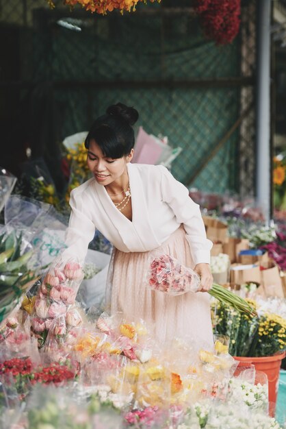 Gut gekleidete asiatische Dame, die Blumen im Blumengeschäft wählt