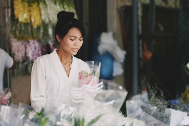 Gut gekleidete asiatische Dame, die Blumenstrauß im Blumenladen wählt