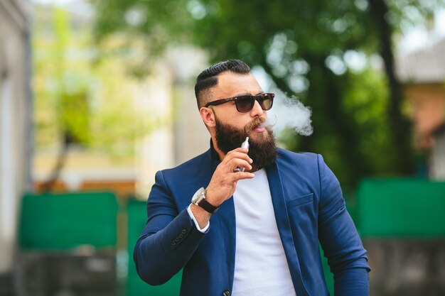 Gut gekleideter Mann, der elektronische Zigarette raucht