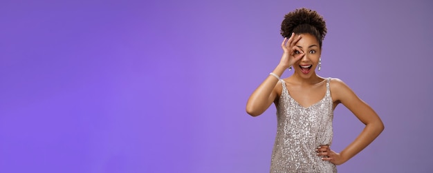 Gutaussehende, charismatische, enthusiastische, flirty afroamerikanische Frau im silbernen Abendkleid hält die Hand