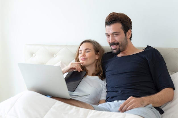 gutaussehender Ehemann und schöne Ehefrau fühlen sich romantisch Paar Filme vom Computer Laptop im Schlafzimmer ansehen