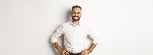 Kostenloses Foto gutaussehender geschäftsmann mit brille, der zufrieden lächelnd aussieht und die hände an der taille hält, die über w steht