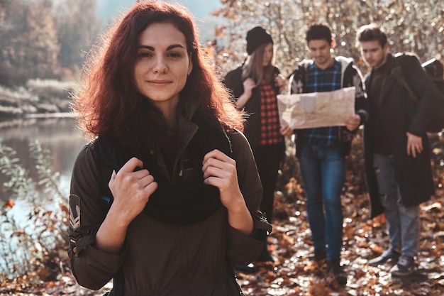 Gute Freunde haben eine schöne Zeit im Herbstwald, sie verwenden eine Karte, um den besten Ort zum Wandern zu finden.