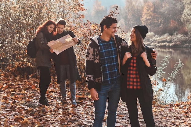 Gute Freunde haben eine schöne Zeit im Herbstwald, sie verwenden eine Karte, um den besten Ort zum Wandern zu finden.