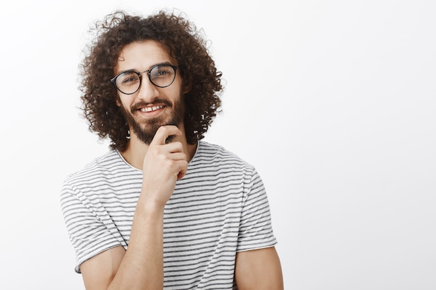 Gute idee, du hast mich fasziniert. porträt des interessierten intelligenten gutaussehenden erwachsenen mannes mit bart und lockigem haar in der trendigen brille