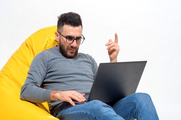 Guy arbeitet mit einem Laptop, während er auf einem gelben Hocker sitzt