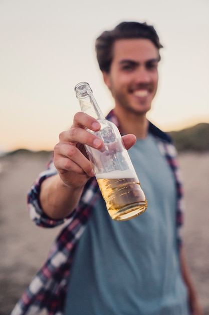 Guy hält Flasche am Strand