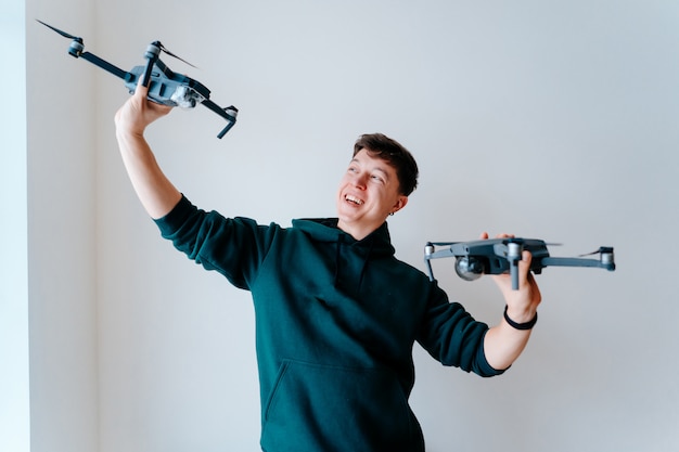 Kostenloses Foto guy hält zwei quadrocopter gegen eine wand