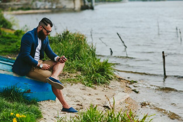 Guy mit seinem Telefon auf einem hölzernen Boot sitzen