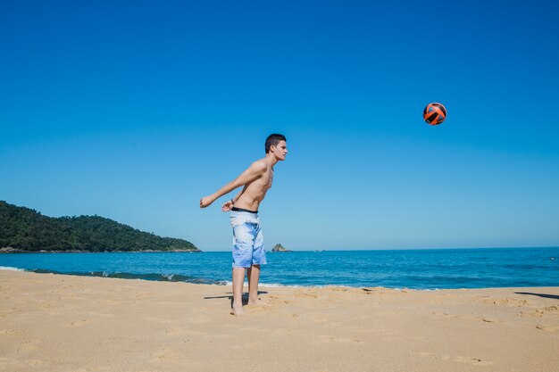 Guy spielt Volleyball am Strand