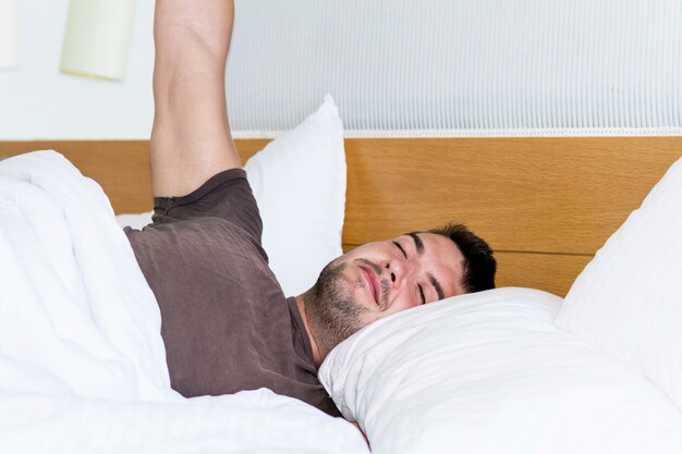 Guy Stretching im Bett nach dem Aufwachen