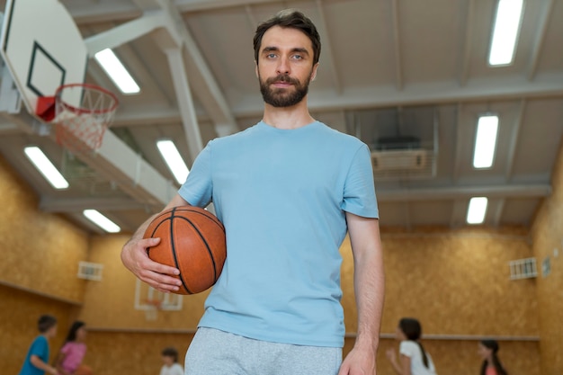 Kostenloses Foto gymnastiklehrer mit mittlerem schuss, der basketball hält