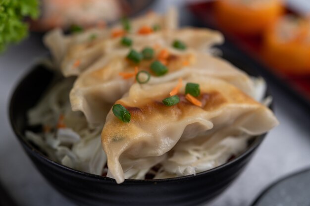 Gyoza in einer schwarzen Tasse mit Sushi.