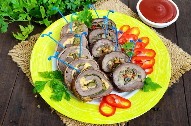 Hackbraten (rolle) mit verschiedenen füllungen (spinat, käse, champignons), in stücke geschnitten auf einem keramikteller mit paprika. festliches fleischgericht.