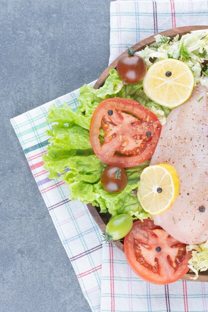 Hähnchenfilets und geschnittenes Gemüse auf Holzteller.