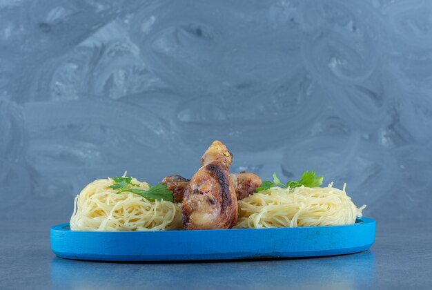 Hähnchenschenkel und Spaghetti auf blauem Teller. k