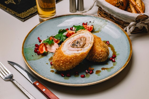 Hähnchenschnitzel von der Seite mit Tomatengrüngranatapfel und Soße auf einem Teller