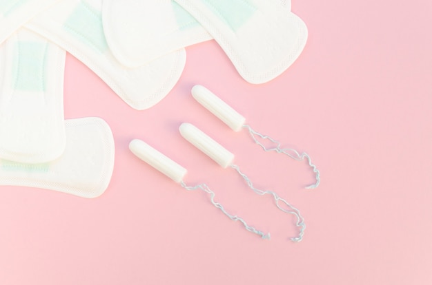 Hälften von Auflagen und von Tampons auf rosa Hintergrund