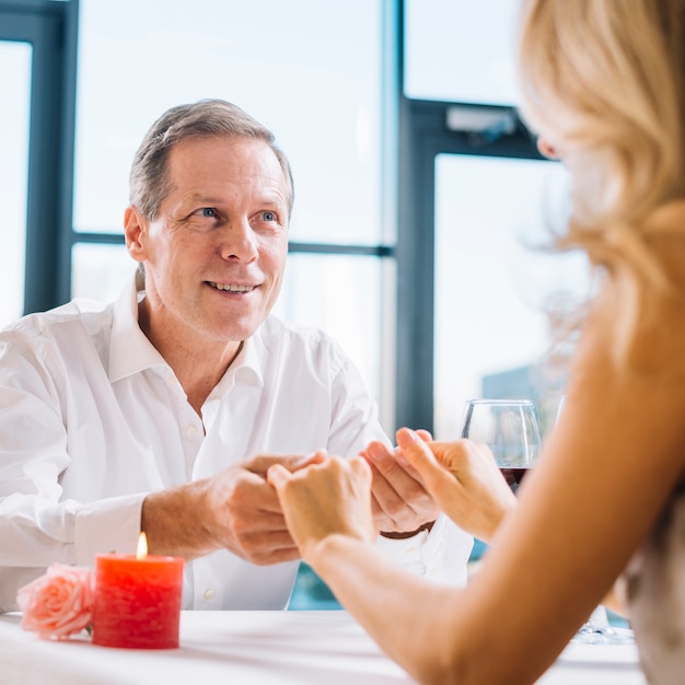 Händchenhalten des verheirateten Paars während des romantischen Abendessens