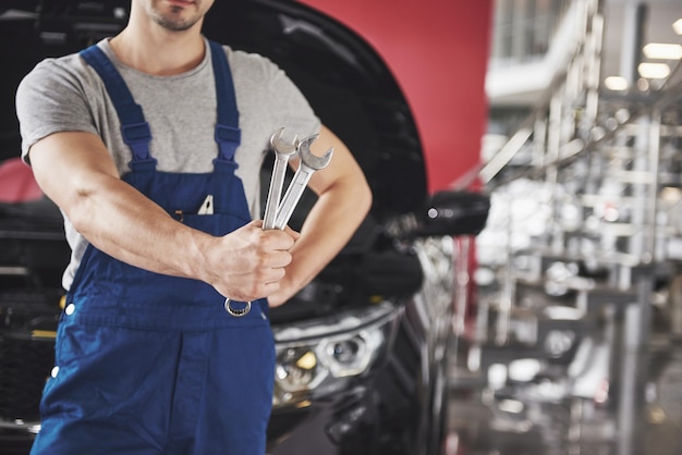 Hände des Automechanikers mit Schraubenschlüssel in der Garage.