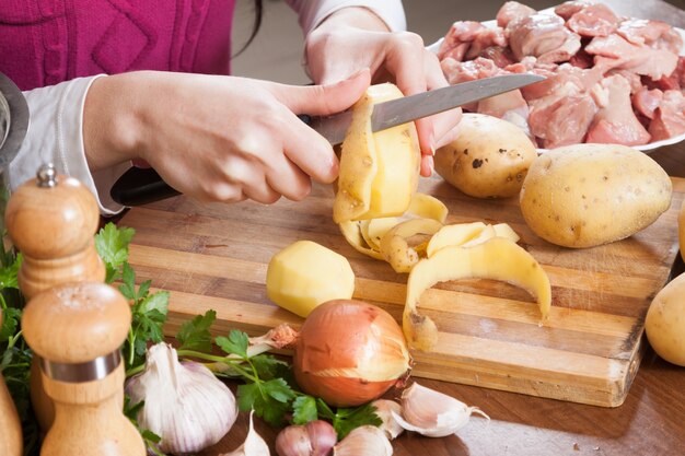 Hände, die bei Tisch Kartoffeln in der Küche säubern