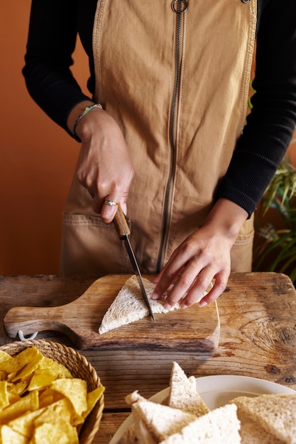 Kostenloses Foto hände, die brot im hohen winkel schneiden