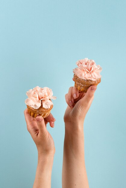 Hände, die Cupcakes mit Blumen halten