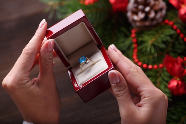 Hände, die eine Box mit einem Ring mit einem blauen Stein