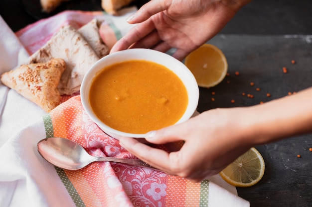 Hände, die eine Schüssel Suppe ergreifen