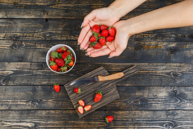 Hände, die Erdbeeren im Holzbrett fangen