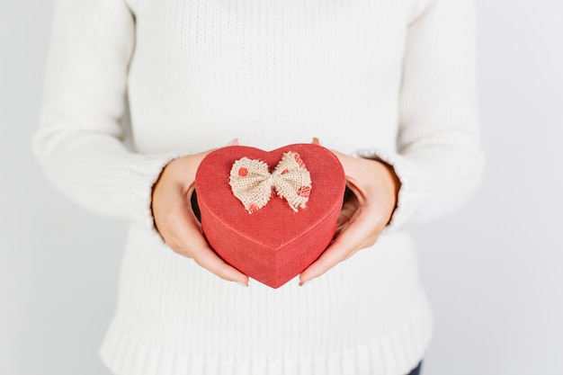 Kostenloses Foto hände, die geformte geschenkbox des roten herzens halten