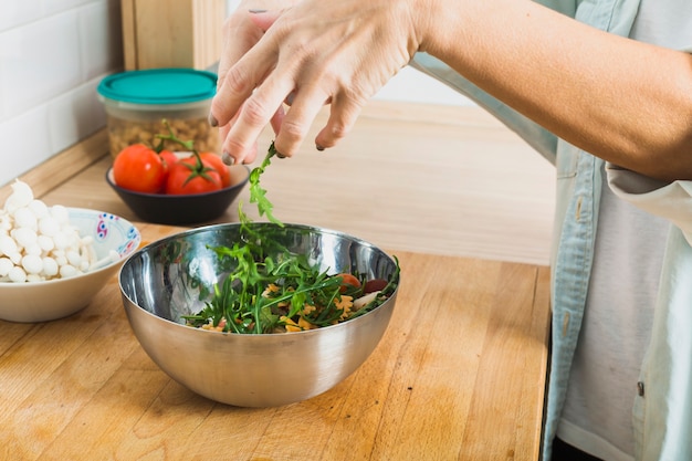 Hände, die grünen Salat in der Küche vorbereiten