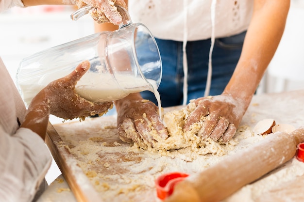 Hände, die Milch gießen, um Teig zuzubereiten