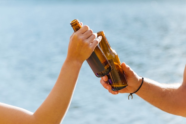 Hände, die mit Flaschen Bier rösten