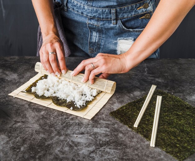 Hände, die mit Sushimatte einwickeln