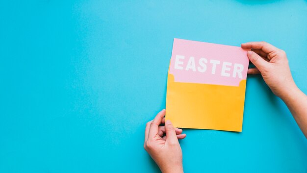 Hände, die Ostern-Wort vom Umschlag herausnehmen