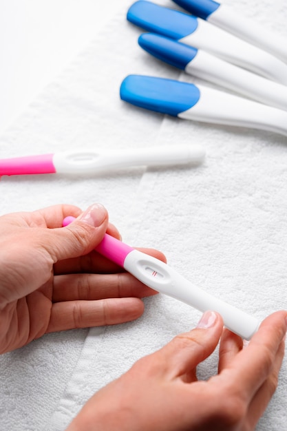 Hände, die positiven Schwangerschaftstest halten