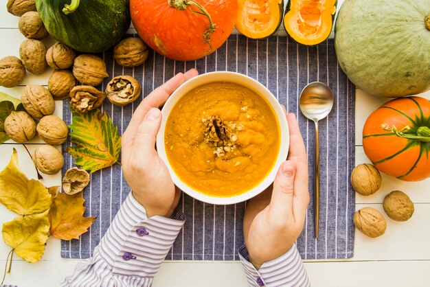 Hände, die Schüssel mit Kürbissuppe halten