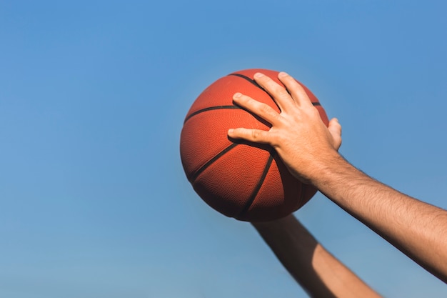 Hände, die Seitenansicht des Basketballs halten