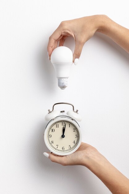 Hände, die Uhr und Glühlampe halten