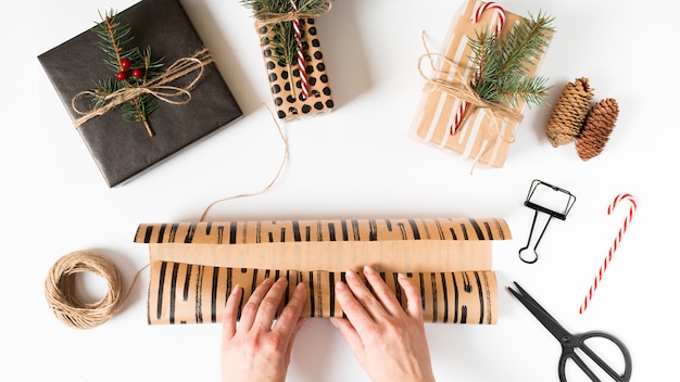 Hände, die Weihnachtsgeschenk im Verpackungspapier einwickeln