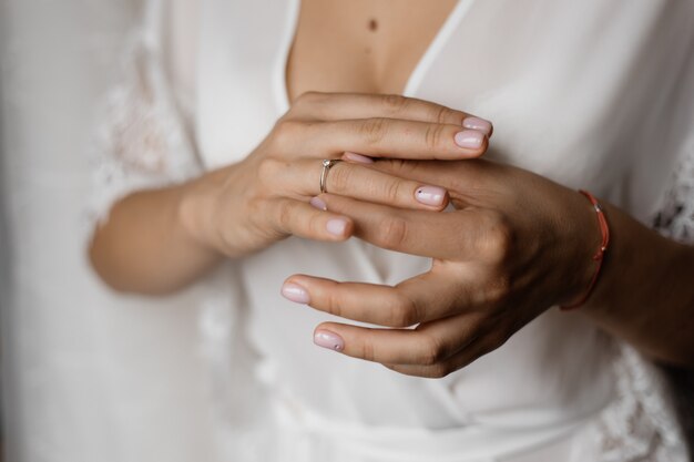 Hände einer Braut mit einem Verlobungsring mit Diamanten und einer zarten Maniküre