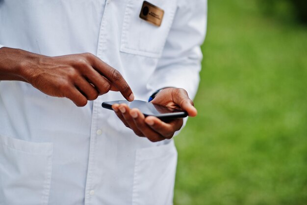 Hände eines afroamerikanischen Arztes, der sein Handy benutzt
