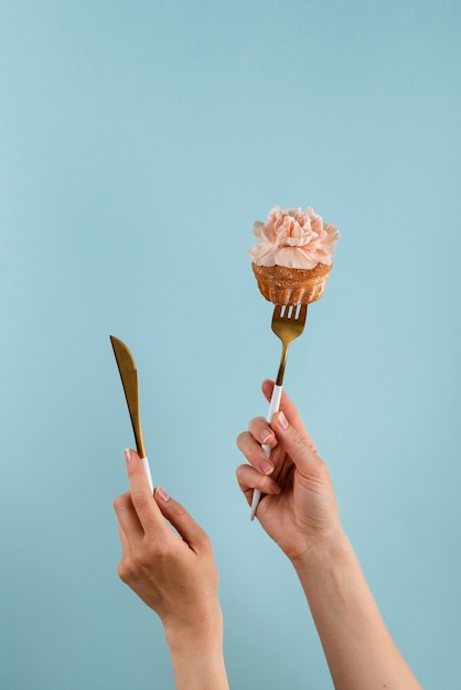 Hände halten Besteck mit Cupcake