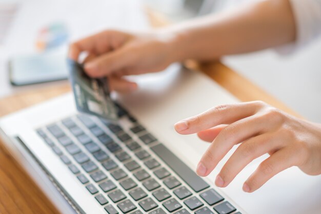 Hände halten eine Kreditkarte und mit Laptop-Computer für Online-Shopping